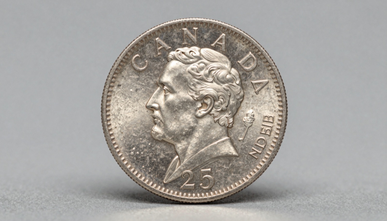 Pre-1968 Canadian silver quarter showing Victoria portrait and detailed caribou reverse on a neutral studio surface