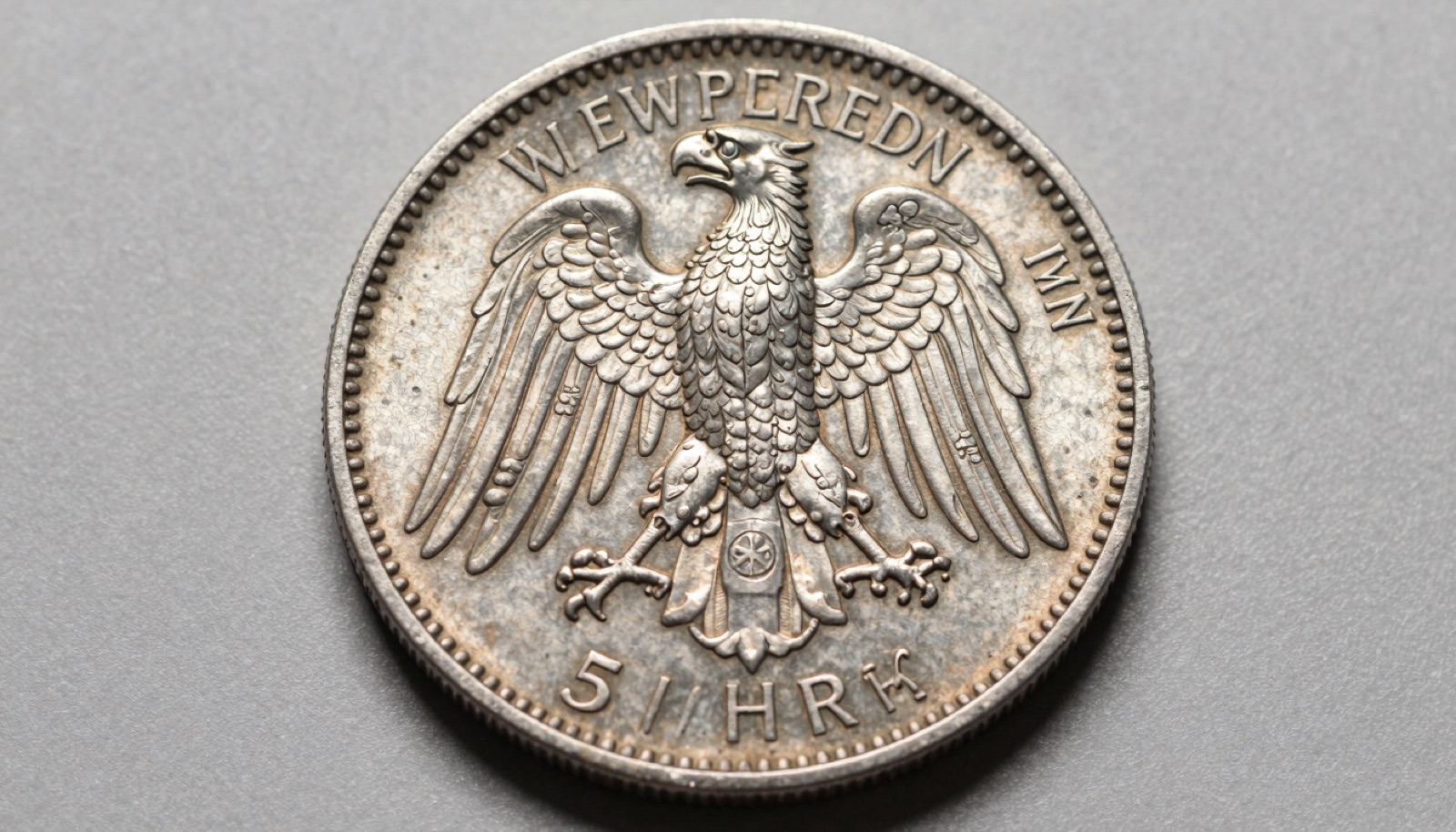 Weimar Republic silver five Reichsmark commemorative coin on neutral studio surface showing detailed eagle reverse and soft cabinet toning