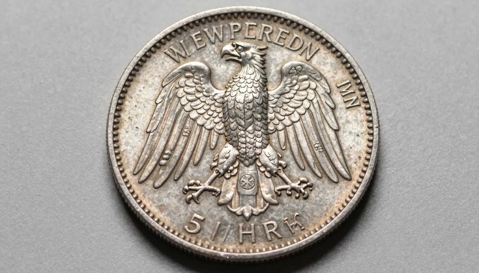 Weimar Republic silver five Reichsmark commemorative coin on neutral studio surface showing detailed eagle reverse and soft cabinet toning