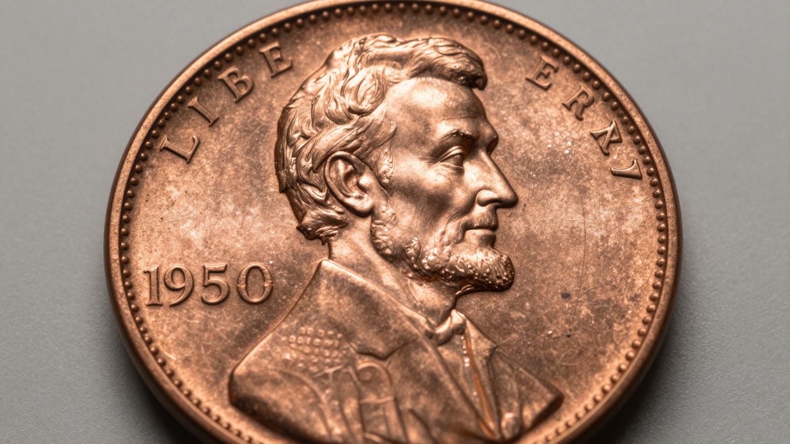Macro photograph of a 1958-D Lincoln wheat penny showing the L in LIBERTY positioned near the raised rim