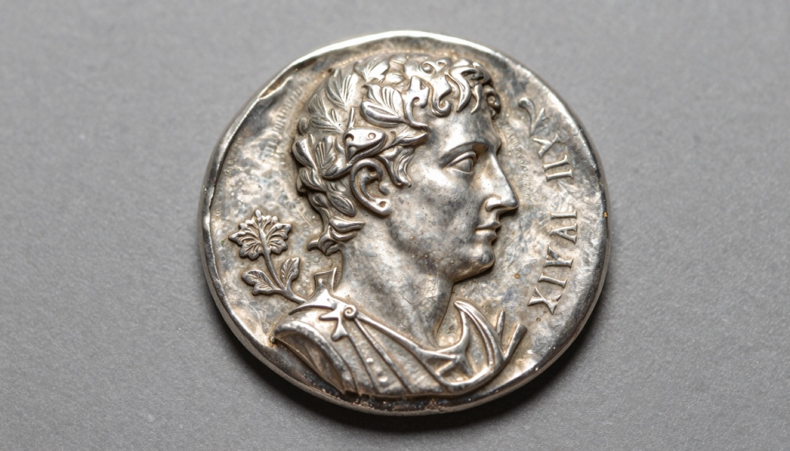 Authentic ancient Roman silver denarius on neutral studio surface showing detailed emperor portrait and reverse deity design