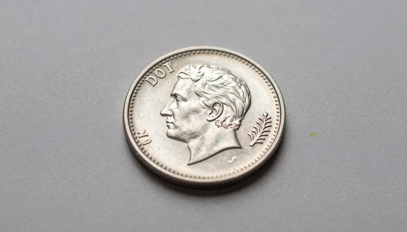 Macro photograph of a silver coin with tape residue partially removed showing clean reflective surface detail