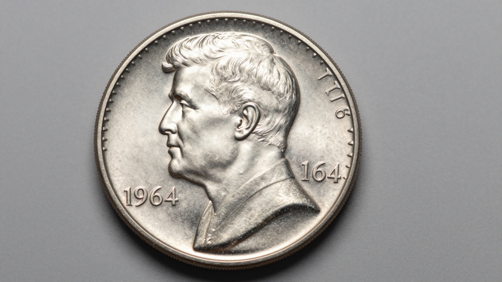 A gem 1964 Kennedy half dollar photographed in macro detail on a neutral gray studio surface